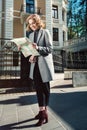 Cute young beautiful curly smiling caucasian travelling woman reading a map