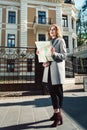 Cute young beautiful curly smiling caucasian travelling woman reading a map