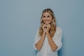 Cute young blonde woman with wavy hairstyle folded hands under her chin and waiting for desired gift