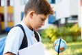 Cute, young boy in blue shirt with backpack and globe in his hands sits on the steps before school. Education, Back to school con Royalty Free Stock Photo