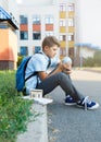 Cute, young boy in blue shirt with backpack stands in front of his school. Education, Back to school Royalty Free Stock Photo