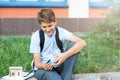 Cute, young boy in blue shirt with backpack stands in front of his school. Education, Back to school Royalty Free Stock Photo