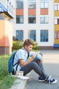 Cute, young boy in blue shirt with backpack stands in front of his school. Education, Back to school Royalty Free Stock Photo