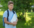 Cute, young boy in blue shirt with backpack and workbooks in his hands in front of his school. Education, Back to school Royalty Free Stock Photo