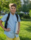 Cute, young boy in blue shirt with backpack and workbooks in his hands in front of his school. Education, Back to school Royalty Free Stock Photo