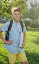 Cute, young boy in blue shirt with backpack and workbooks in his hands in front of his school. Education, Back to school Royalty Free Stock Photo