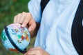 Cute, young boy in blue shirt with backpack and workbooks holds globe in his hands in front of his school. Education Royalty Free Stock Photo