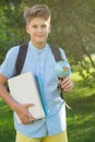 Cute, young boy in blue shirt with backpack and workbooks holds globe in his hands in front of his school. Education Royalty Free Stock Photo