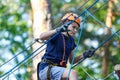 Cute young boy in helmet with climbing equipment in the rope amusement park. Summer camp Royalty Free Stock Photo