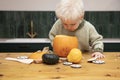 A cute young boy peering into a halloween pumpkin whilst making a lantern decoration