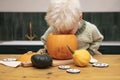 A cute young boy peering into a halloween pumpkin whilst making a lantern decoration