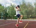 Cute young boy plays basketball on street playground in summer. Teenager in white t-shirt with orange basketball ball outside. Royalty Free Stock Photo