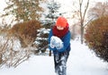 Cute young boy in red hat blue jacket holds and plays with snow, has fun, smiles, makes snowman in winter park. Royalty Free Stock Photo