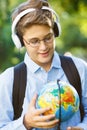 Cute young boy in round glasses and blue shirt stands on the grass and holds a globe in his hands in the park. Education Royalty Free Stock Photo