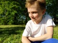 A cute young boy smiling and looks to the side. The child is dressed in a white T-shirt and blue pants. Blond hair is beautiful Royalty Free Stock Photo