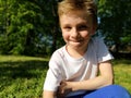 A cute young boy smiling and looks to the side. The child is dressed in a white T-shirt and blue pants. Royalty Free Stock Photo