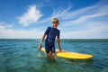 Cute young boy stand with orange surfboard in ocean Royalty Free Stock Photo