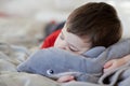 cute young boy taking a nap on the bed using his plush toy as a pillow