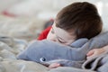 cute young boy taking a nap on the bed using his plush toy as a pillow