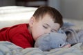 cute young boy taking a nap on the bed using his plush toy as a pillow