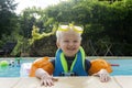 A cute young boy wearing arm bands and goggles having fun in a swimming pool on holiday Royalty Free Stock Photo