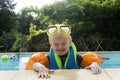 A cute young boy wearing arm bands and goggles having fun in a swimming pool on holiday Royalty Free Stock Photo