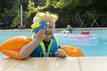 A cute young boy wearing arm bands and goggles playing with a water pistol in a swimming pool Royalty Free Stock Photo