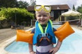 A cute young boy wearing arm bands and goggles standing on the edge of swimming pool Royalty Free Stock Photo