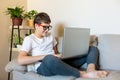 Cute young boy white t shirt sitting on the couch in the living room with his finger up next to laptop and study. Home education Royalty Free Stock Photo