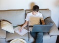Cute young boy in white t shirt sitting on the couch in the living room with laptop and study. Homeschooling, self education