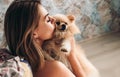 Cute young brunette girl kisses her Pomeranian spitz dog. The concept of home comfort and pet care Royalty Free Stock Photo