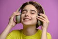 Cute young brunette having fun listening music using wireless headphones