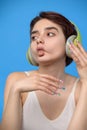 Cute young brunette making fish lips while listening music using wireless headphones