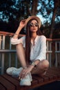 Pretty brunette in straw hat, short shorts and sunglasses in a summer park Royalty Free Stock Photo