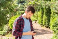 Cute young Caucasian man in a plaid shirt writes SMS. The guy is waiting for the girl on a date and is texting in the messenger