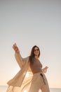 Cute young caucasian vigorously dancing outdoors against backdrop of sky.