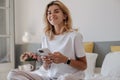 Cute young caucasian woman wears white t-shirt using her smartphone and looking at camera indoor. Royalty Free Stock Photo