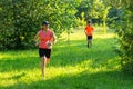 Cute young caucasian women wearing sportswear running through a forest during exercise in outdoor orienteering