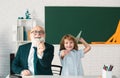 Cute young child in class at school. Senior teacher and at home working. Elderly teacher trainer teen pupil boy Royalty Free Stock Photo