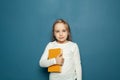 Cute young child girl with book standing against bright blue studio wall background Royalty Free Stock Photo