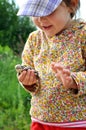 A cute young child girl holding a frog toad in hands and laughing