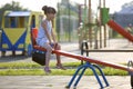 Cute young child girl outdoors on see-saw swing on sunny summer day