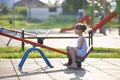 Cute young child girl outdoors on see-saw swing on sunny summer day