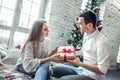 Merry Christmas and Happy Holidays! Cute, young couple exchanging Christmas presents on Christmas morning Royalty Free Stock Photo