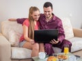 Cute young couple having breakfast, in front of laptop computer Royalty Free Stock Photo