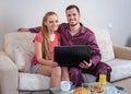 Cute young couple having breakfast, in front of laptop computer Royalty Free Stock Photo