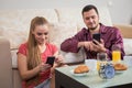 Cute young couple having breakfast and looking at mobile phone Royalty Free Stock Photo