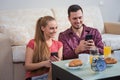 Cute young couple having breakfast, photographs at mobile phone