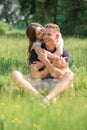 Cute young couple sitting on grass, kissing. Young man and woman enjoying summer day. Happy people in love, honey moon