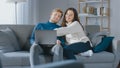 Cute Young Couple Use Laptop Computer, Have Fun, Laughs, while Sitting on the Couch in the Cozy Royalty Free Stock Photo